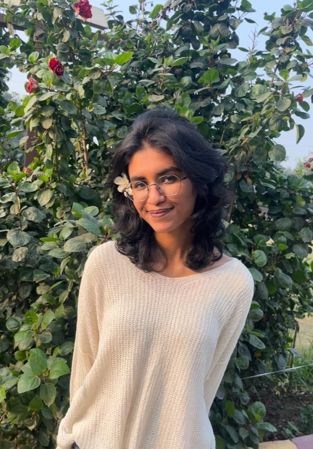 Anushka Sree standing before a flowering hedge