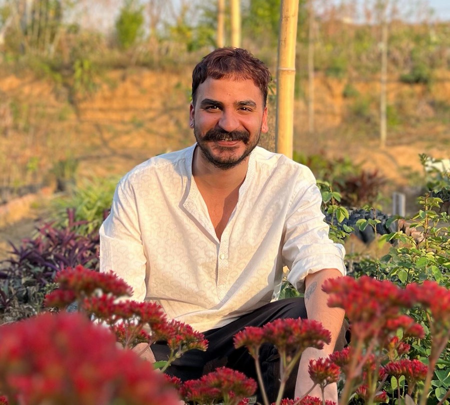 Ashim Bery seated outdoors behind red flowering plants