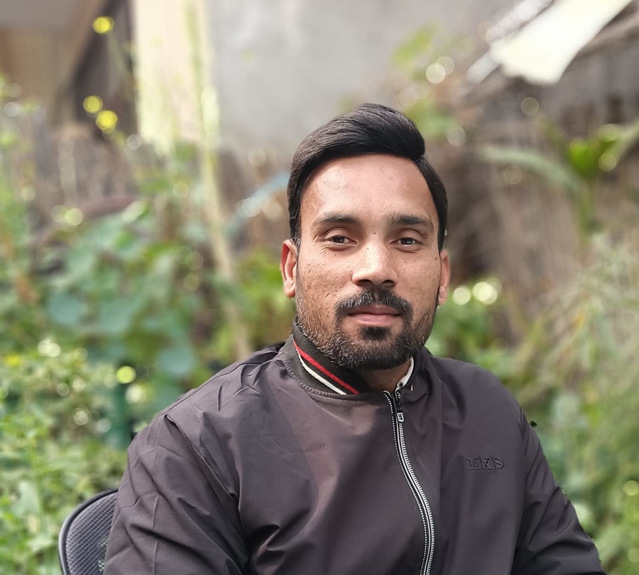 Neeraj Kumar, seated portrait against blurred greenery