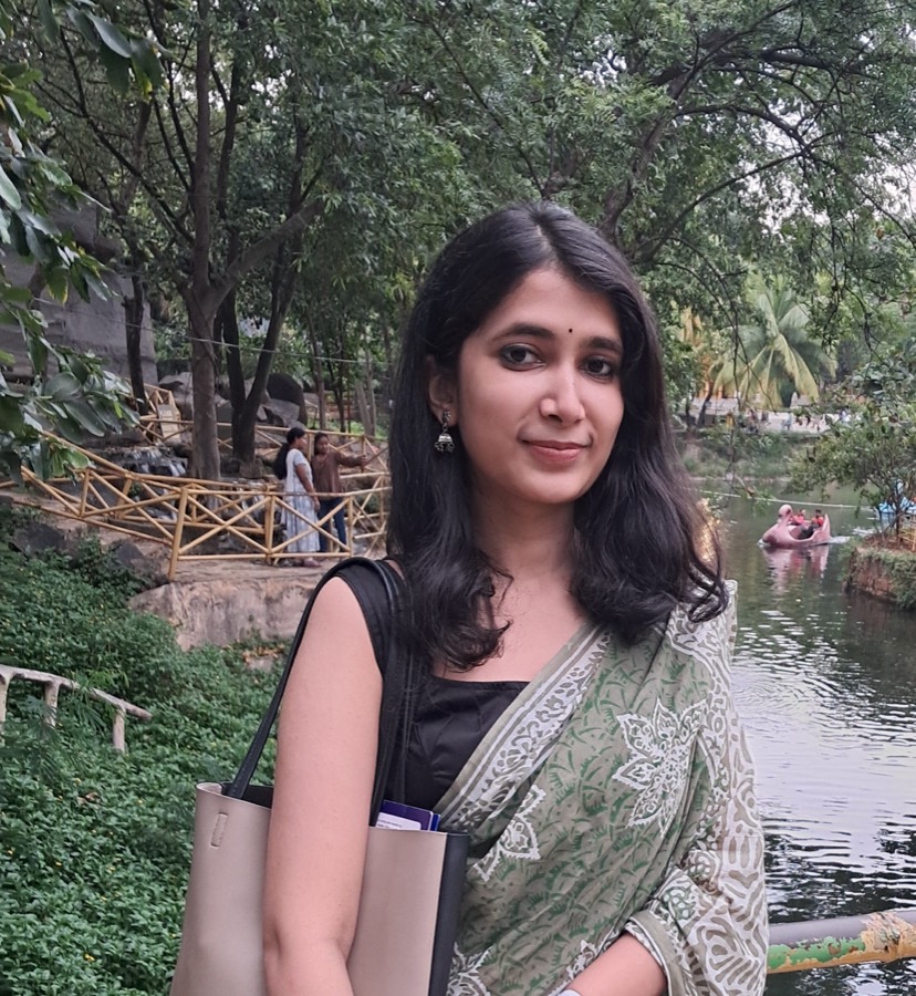 Srija Bandyopadhyaya beside a railed pond, holding a folder