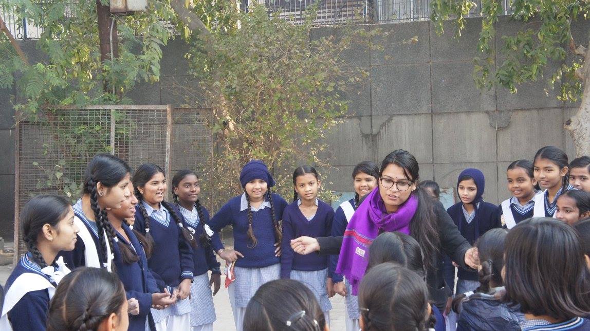 Placeholder frame: a facilitator addressing a semicircle of girls in winter uniform