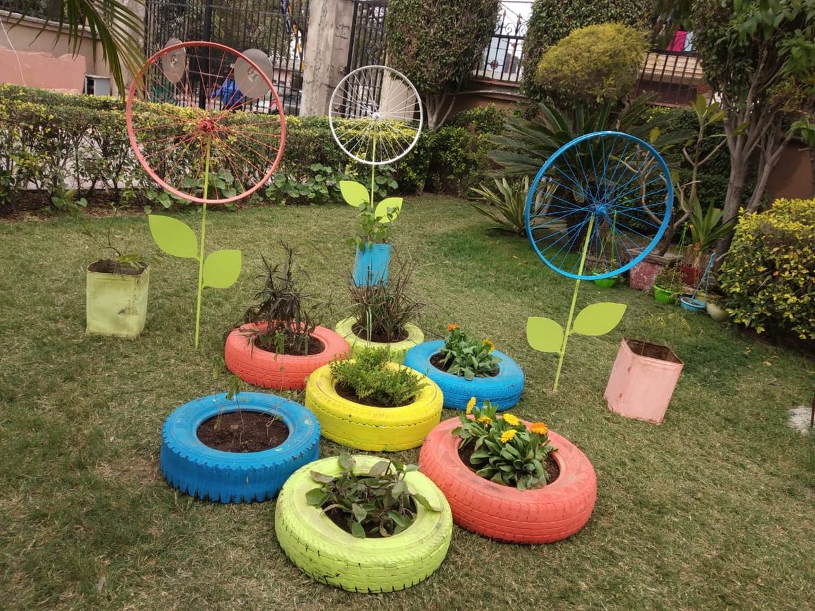 A lawn planted up with old tyres and bicycle wheels painted and repurposed as flower beds