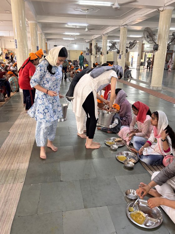Volunteers serving a shared meal to a seated gathering