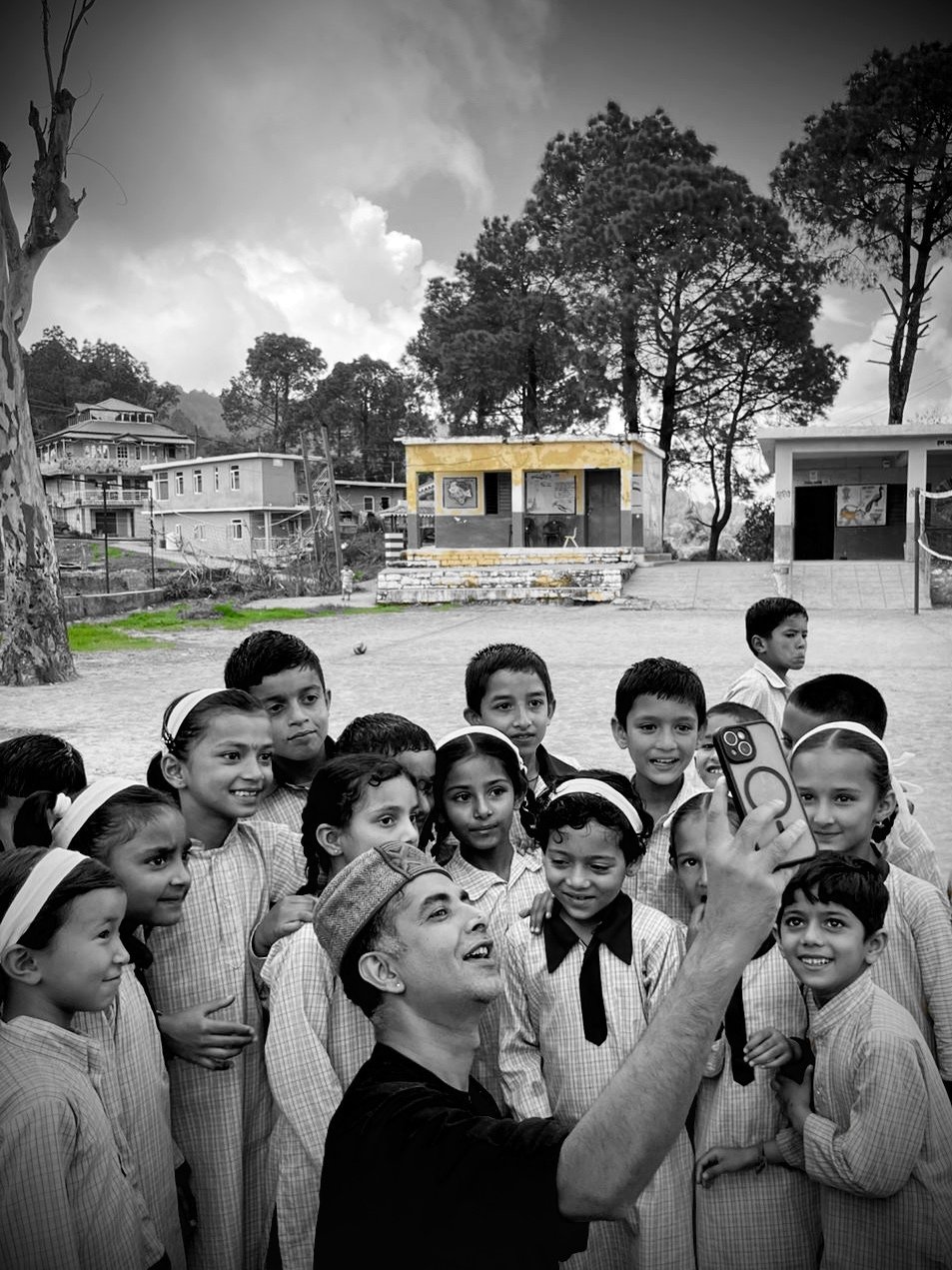 A facilitator taking a phone photograph with a crowd of uniformed schoolchildren