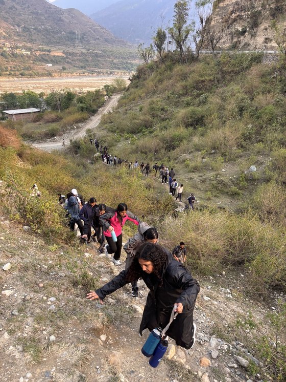 A long line of trekkers crossing a hillside