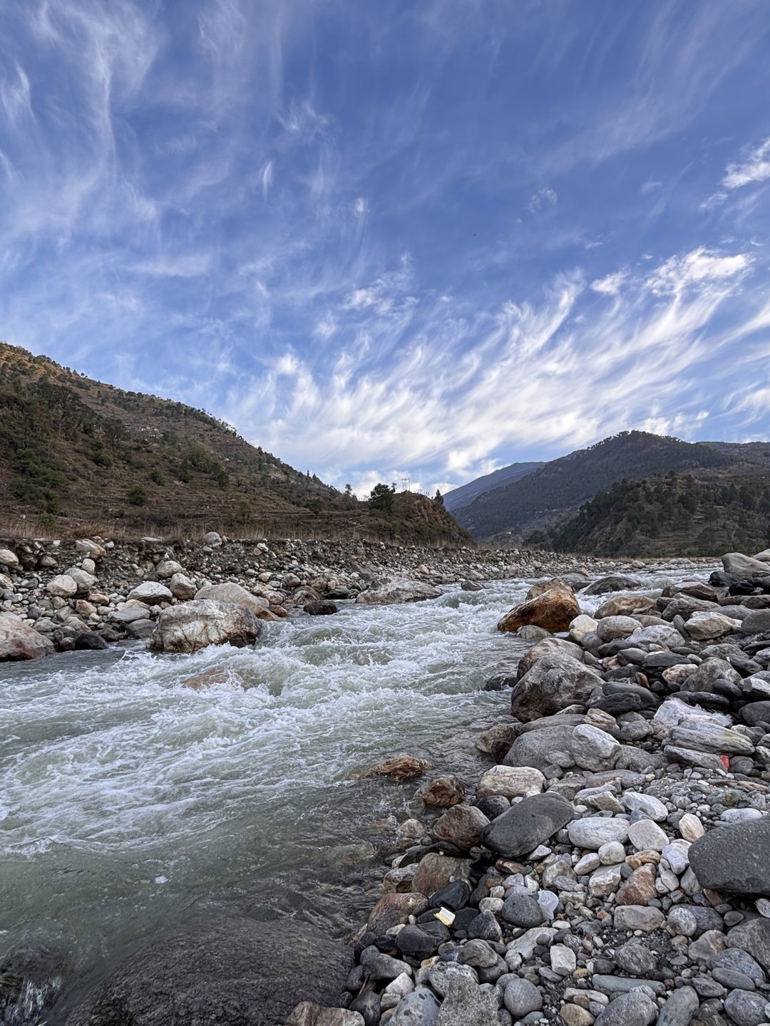 The Yamuna running fast over rocks below Himalayan slopes