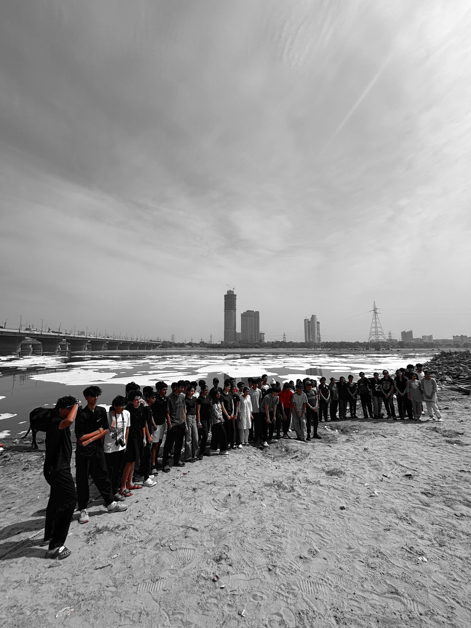 A long line of students facing the Yamuna, the city skyline behind